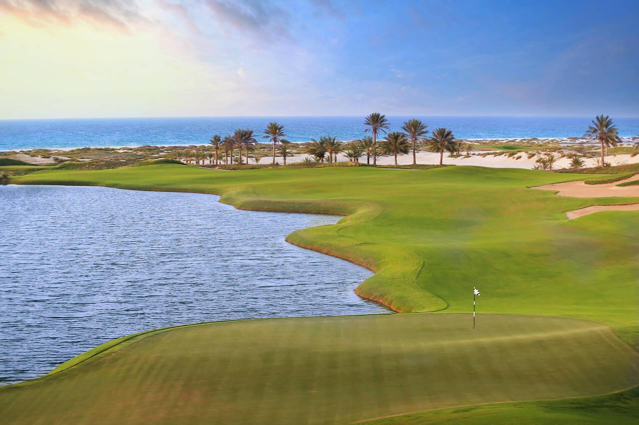 A well maintained fairway leading to a smooth green next to a water hazard