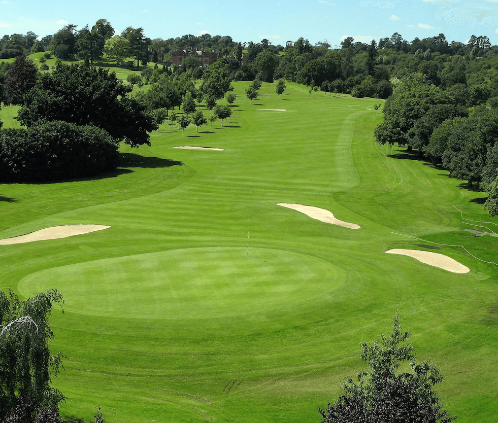 A well maintained fairway nestled with sand bunkers leading to a smooth green