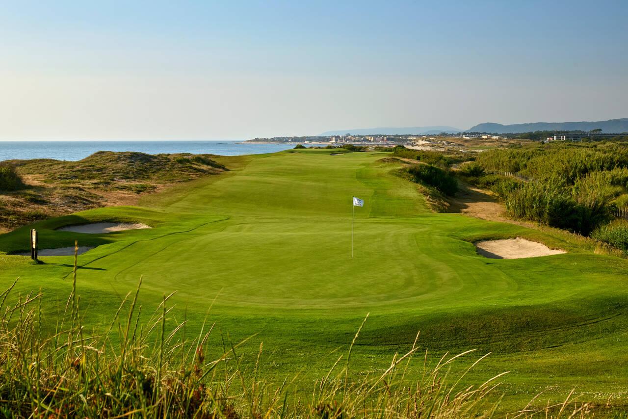 A well maintained fairway leading to a smooth green under clear blue skies
