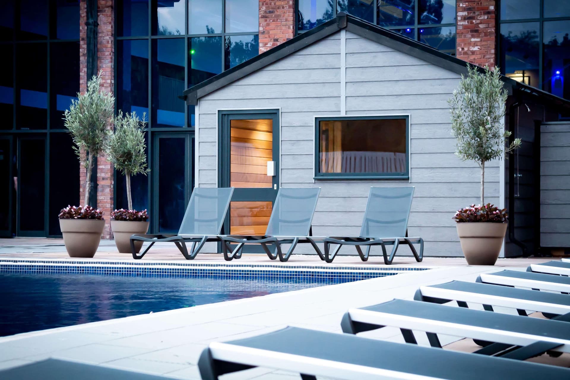 Outdoor swimming pool surrounded by sunbeds at Village Hotel Herons Reach