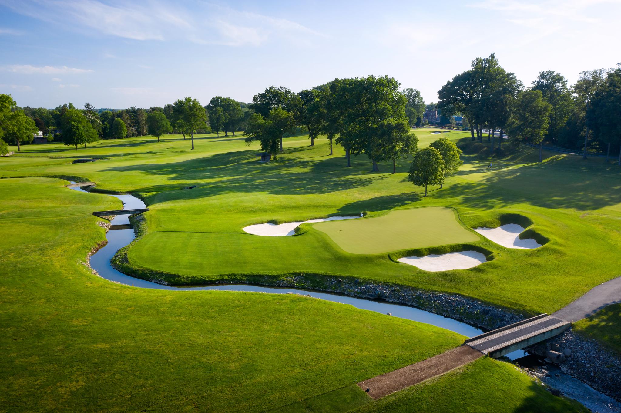 A well maintained golf fairway in the USA leading to a smooth green surrounded by sand bunkers