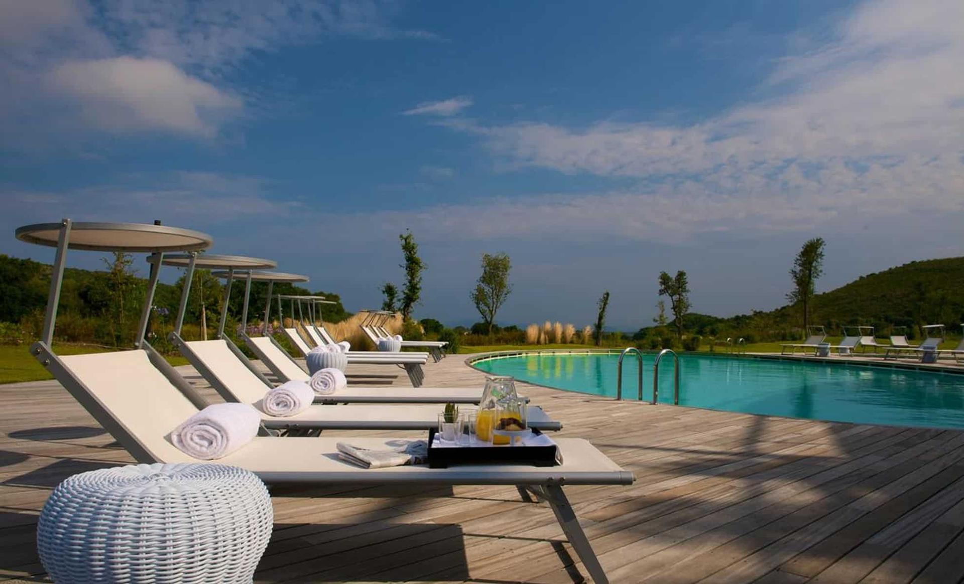Outdoor pool surrounded by sunbeds at Argentario Resort Golf and Spa