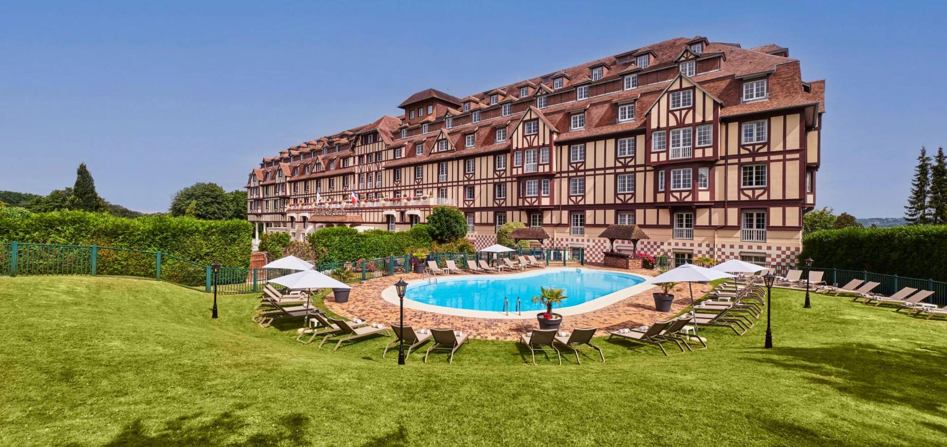 Panoramic view of the Hotel Barriere L'Hotel du Golf building overlooking outdoor pool