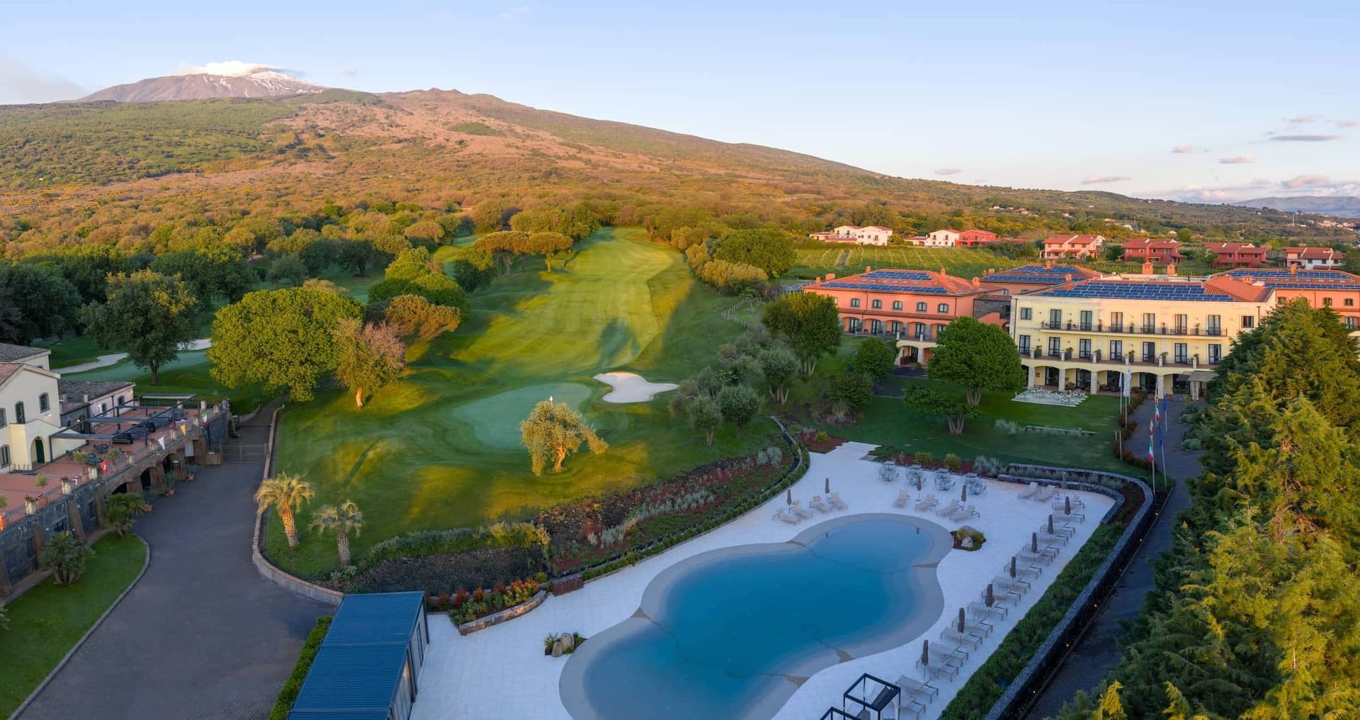 Overhead view of he outdoor pool, golf course and building at Il Picciolo Etna Golf Resort & Spa, Curio Collection by Hilton