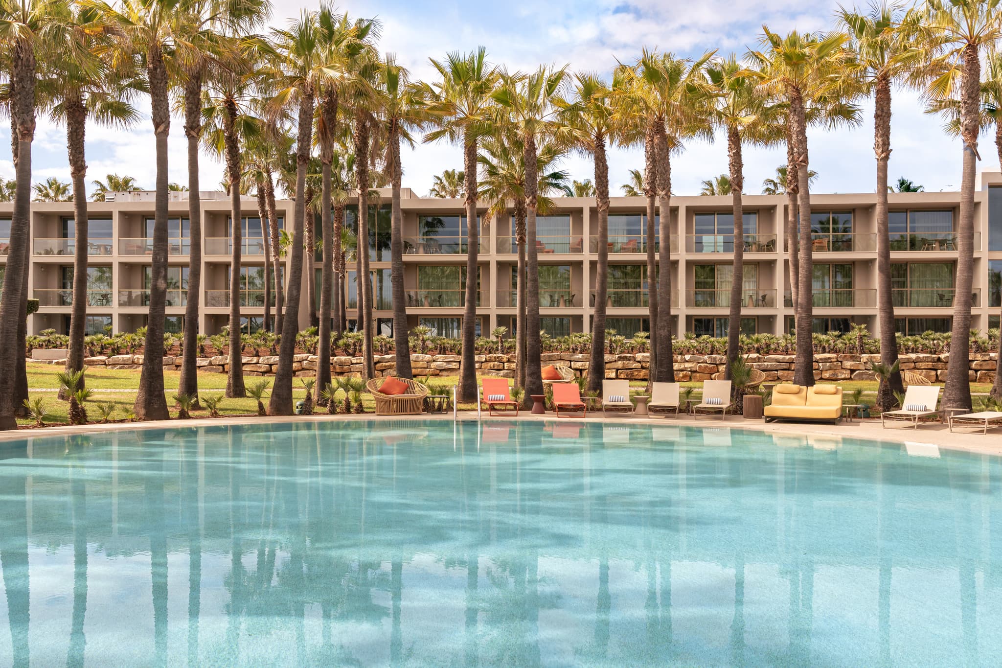 Outdoor swimming pool at Kimpton Atlantico Algarve surrounded by palm trees
