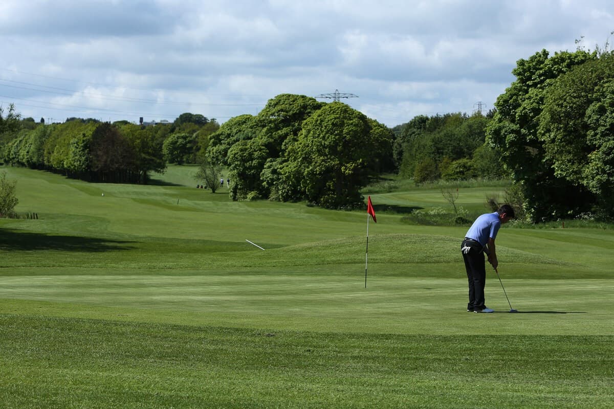 Golfer putting on a smooth green with a red flagstick