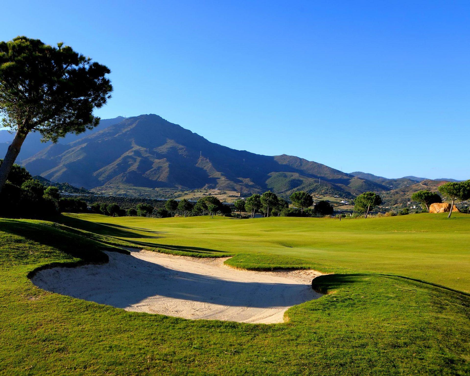 A sand bunker on a well maintained fairway with distant mountain views