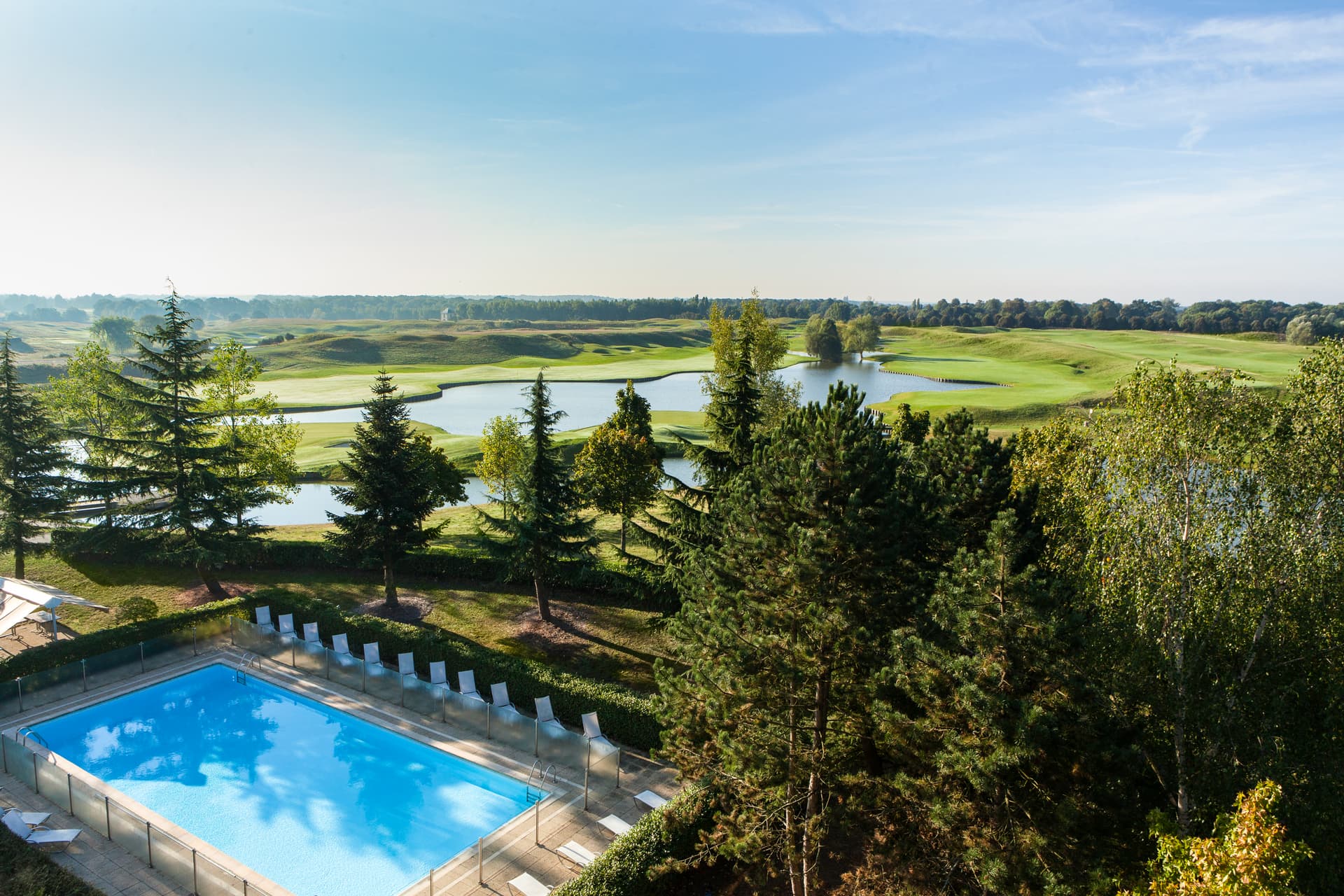 The outdoor swimming pool at Novotel Saint Quentin en Yvelines overlooking the neighbouring golf course