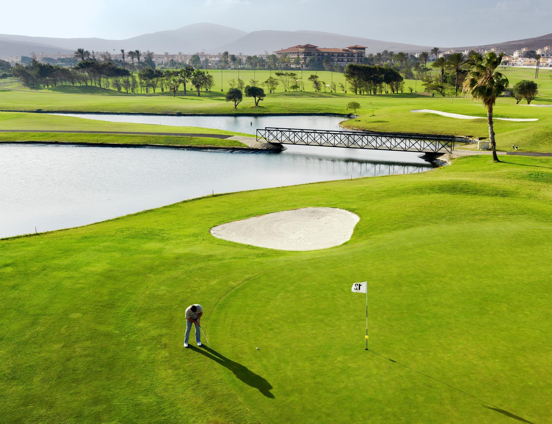 A well maintained fairway leading to a smooth green next to a sand bunker