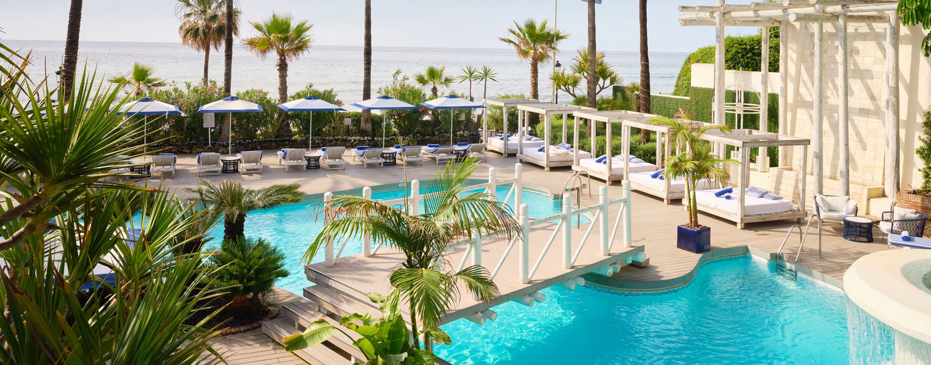 Outdoor swimming pool with a bridge to navigate the resort at Puente Romano Beach Resort