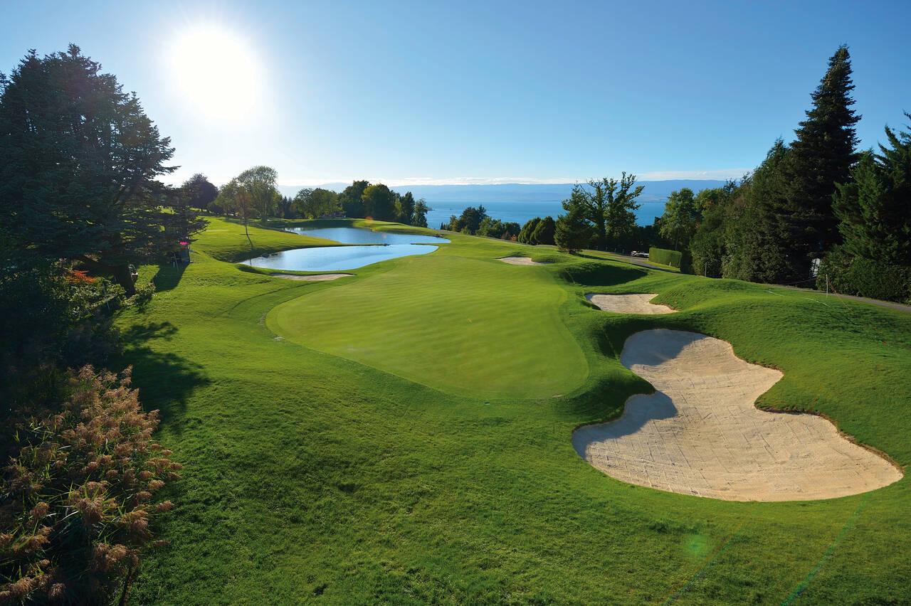 A smooth green sandwiched by a large sand bunker and a water hazard