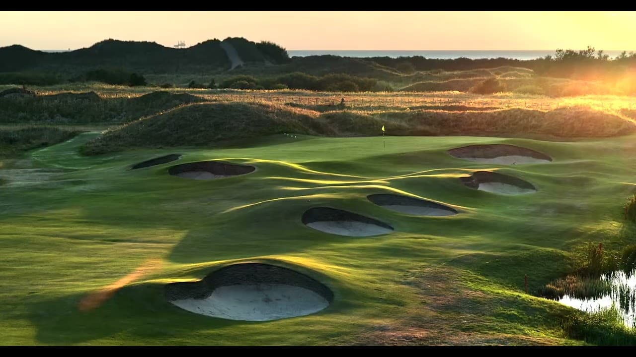 A well maintained fairway nestled with sand bunkers under sunset