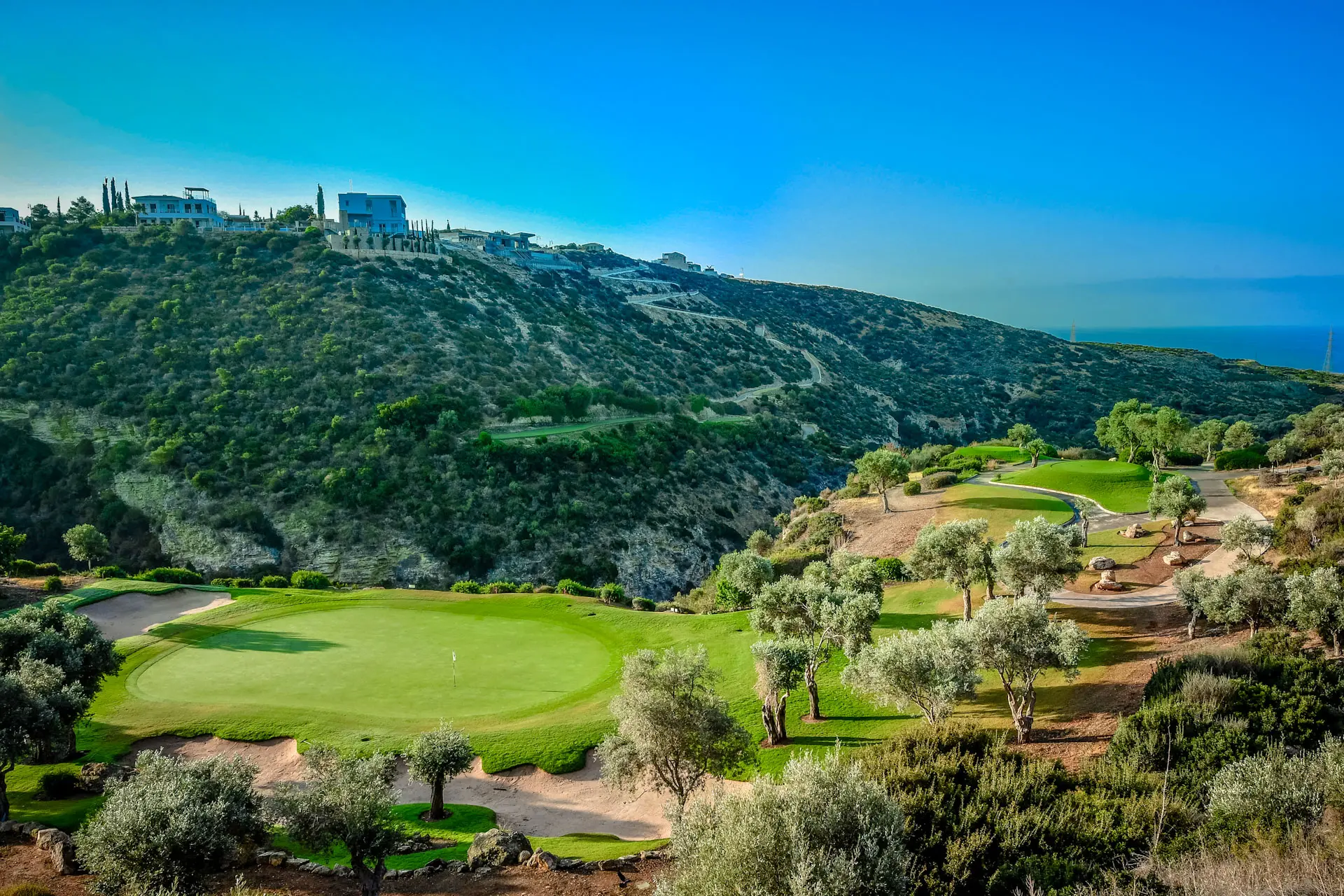 A smooth green with distant mountain views at Aphrodite Hills Resort
