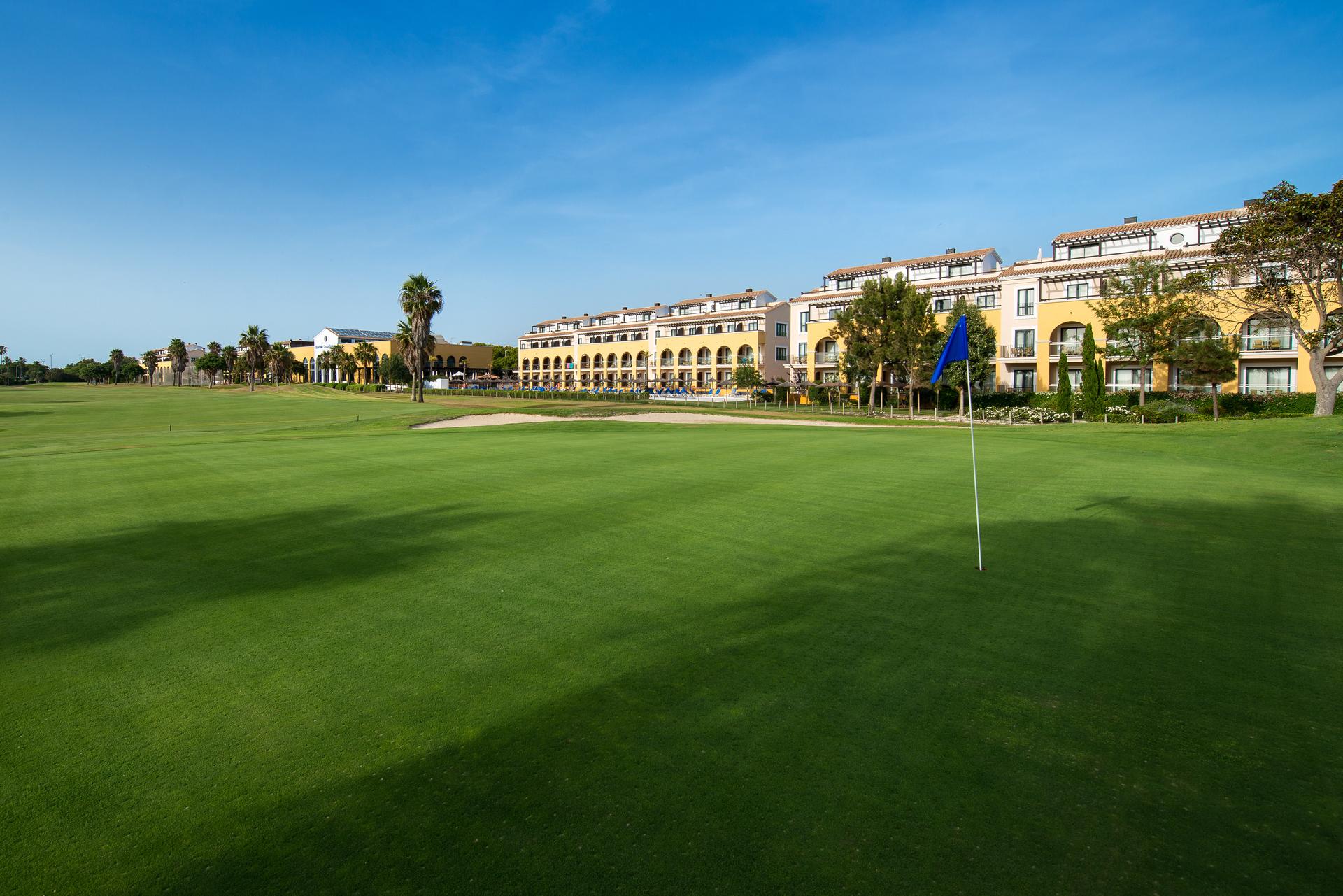 The Barcelo Costa Ballena Golf & Spa building overlooking a smooth green with a blue flagstick