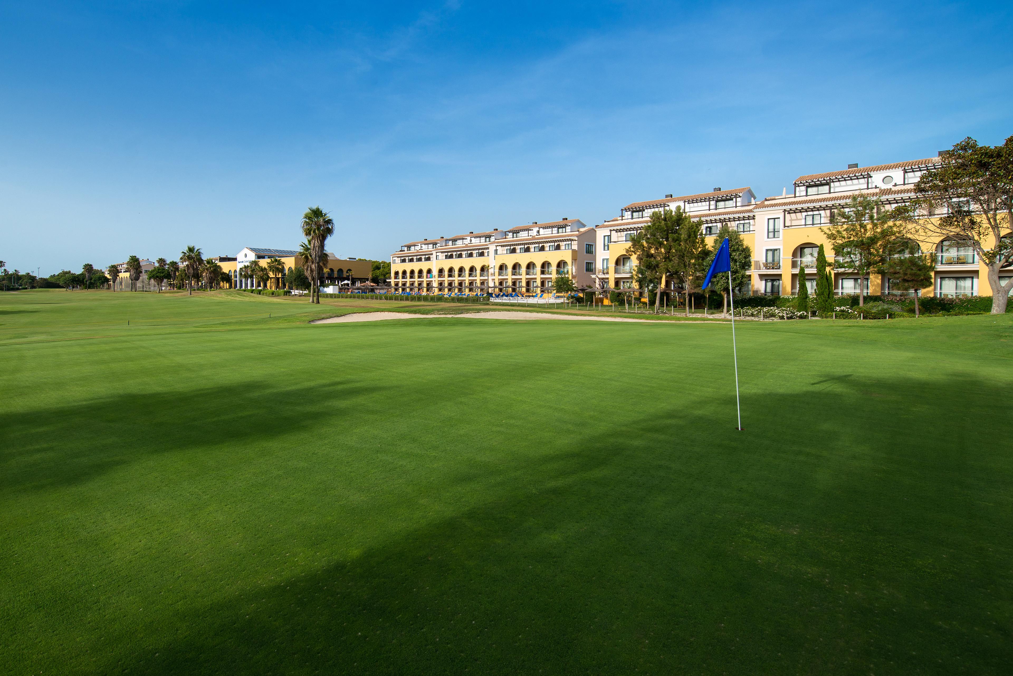 The Barcelo Costa Ballena Golf & Spa building overlooking a smooth green with a blue flagstick