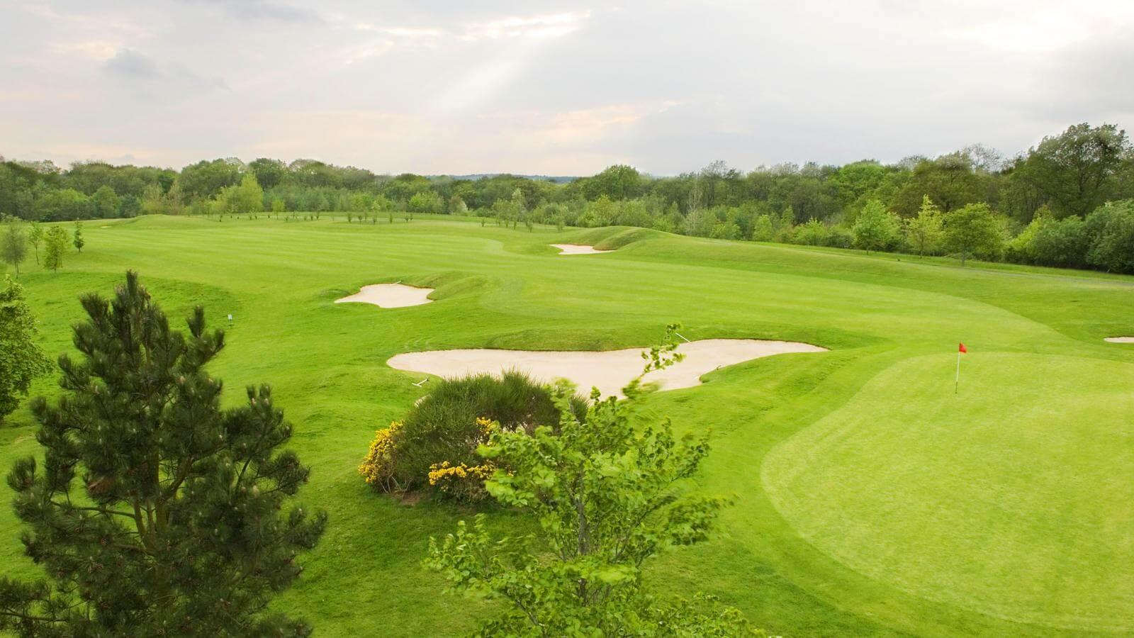 A well maintained fairway nestled with sand bunkers leading to a smooth green