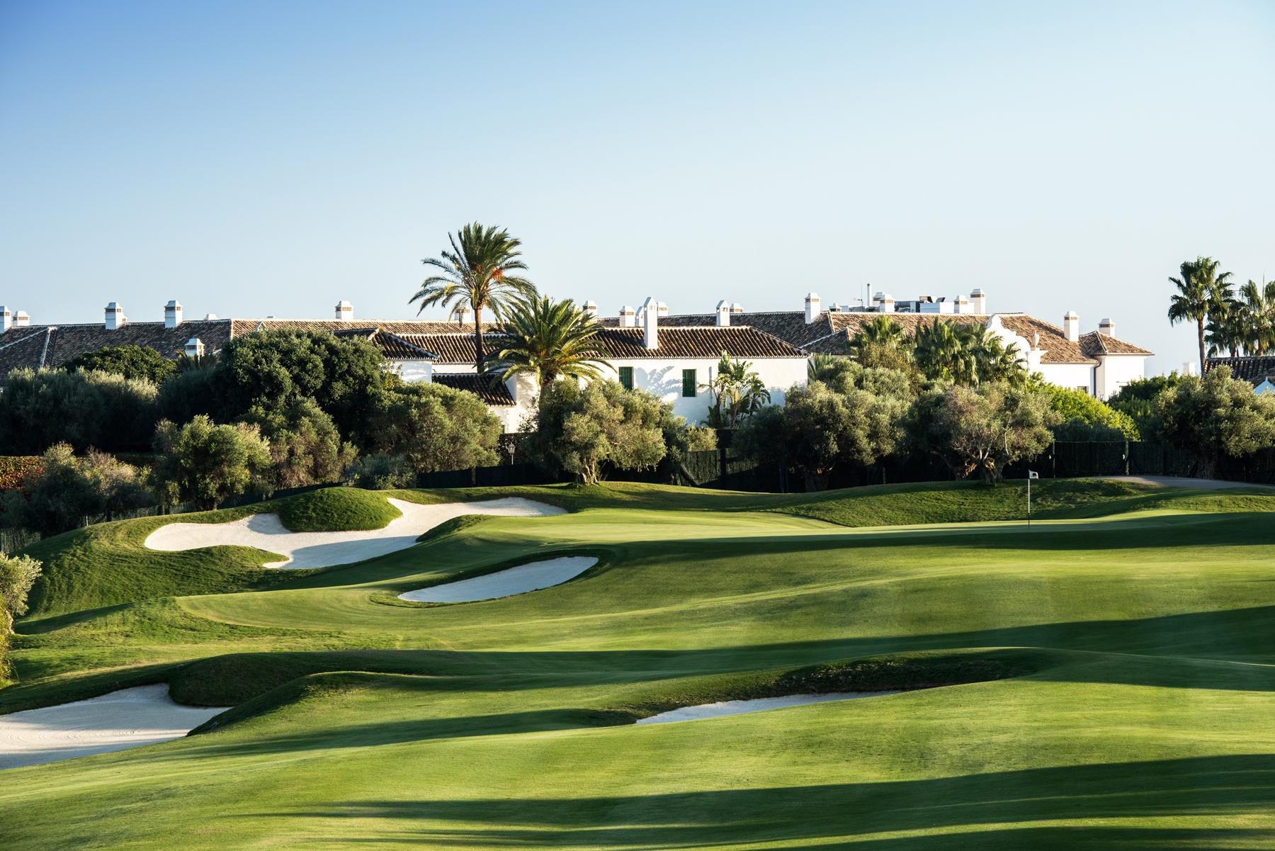A well maintained fairway nestled with sand bunkers under clear blue skies