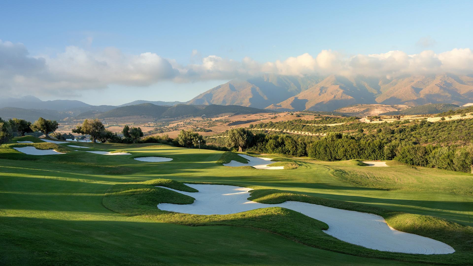 A well maintained fairway nestled with sand bunkers and mountain views in the distance