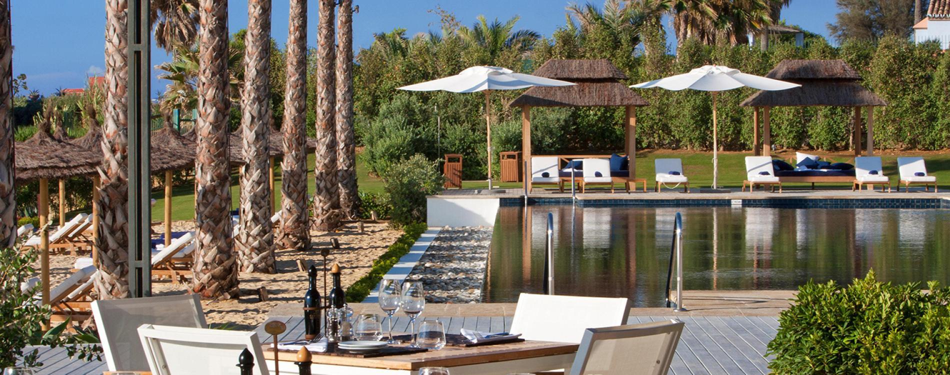 Outdoor swimming pool surrounded by sunbeds at Finca Cortesin Hotel