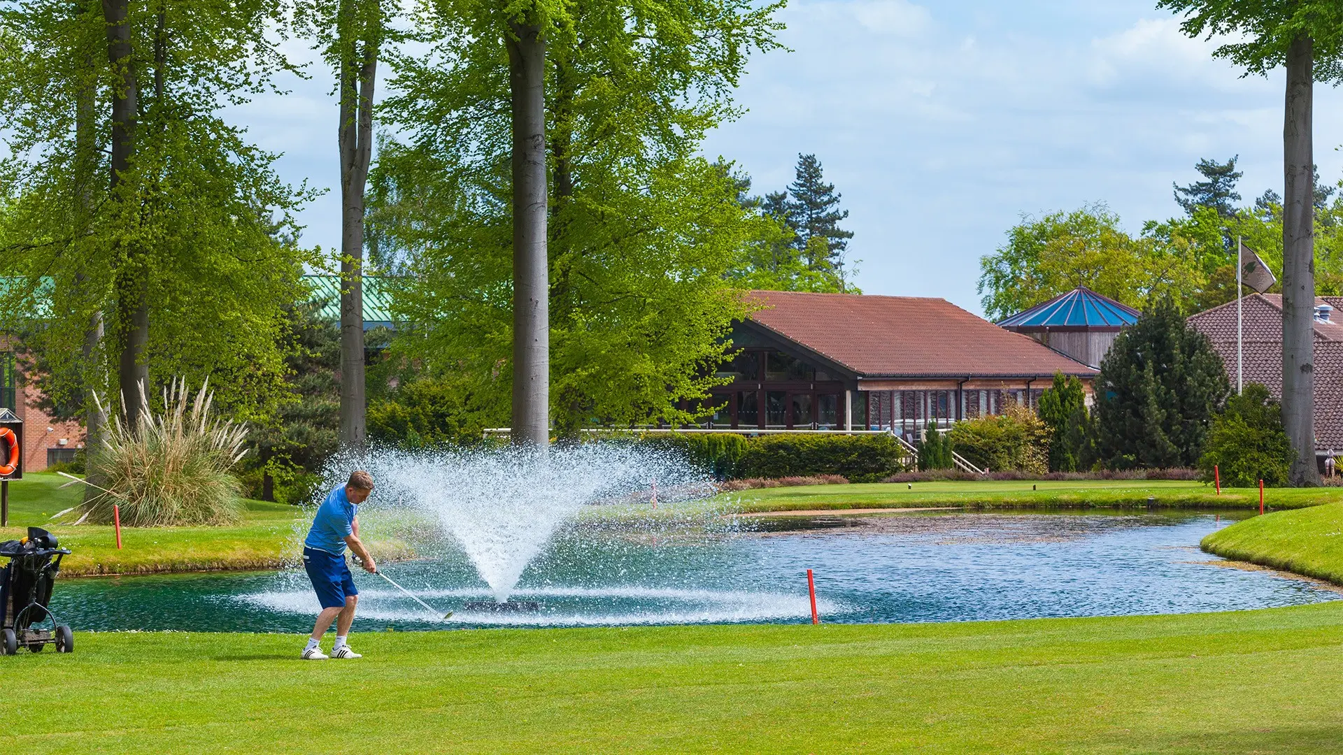 Golfer swinging over a water hazard towards the clubhouse