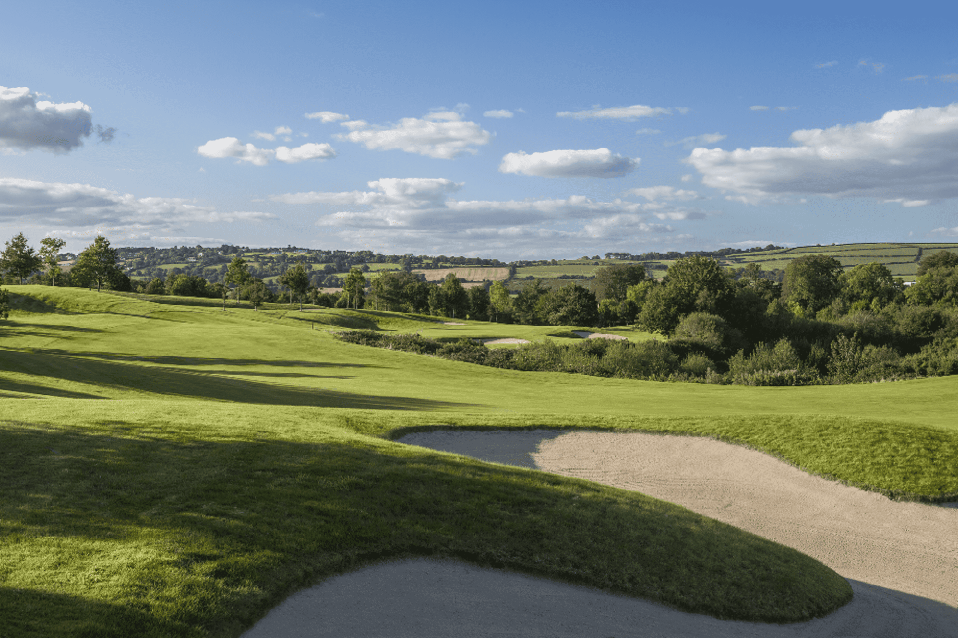 A well maintained fairway nestled with a sand bunker