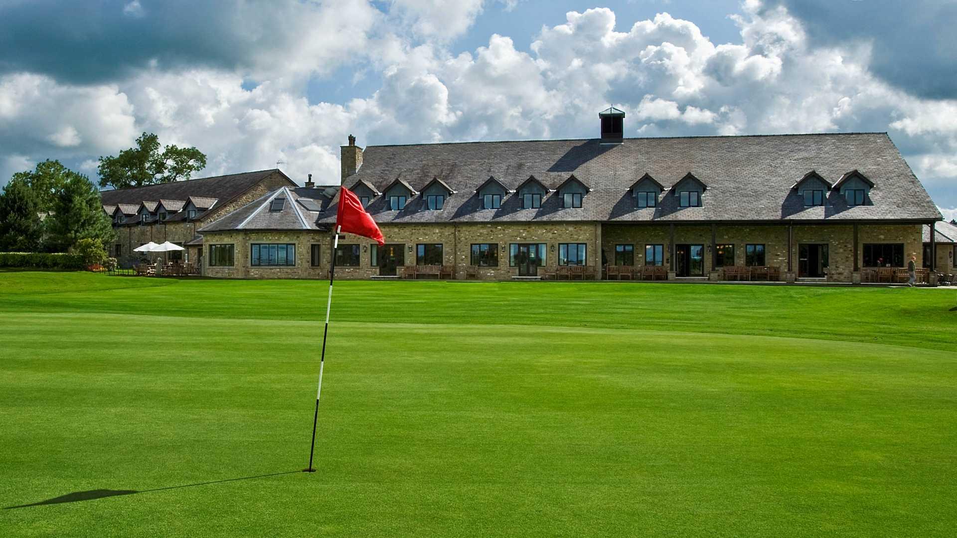 A smooth green with a flagstick and clubhouse in the back