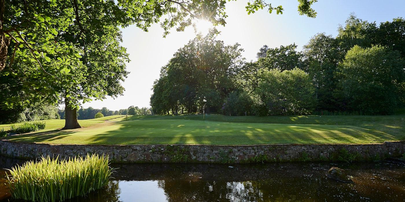 Sloping green down to a water hazard