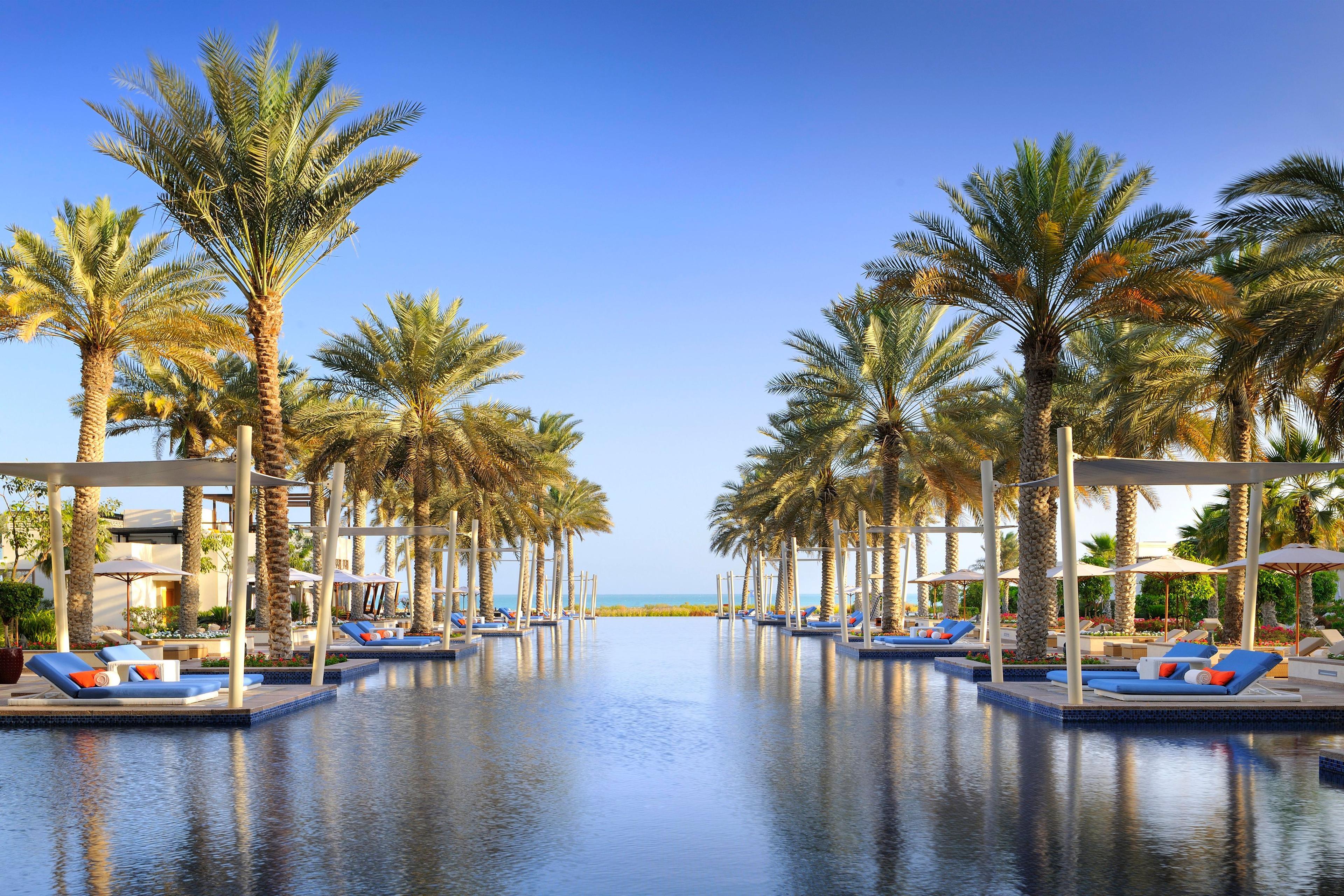 Outdoor swimming pool lined with palm trees at the Park Hyatt Abu Dhabi Hotel and Villas