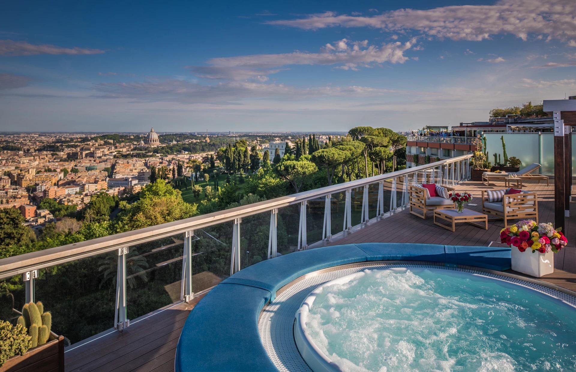 A balcony with a jacuzzi and views of the city
