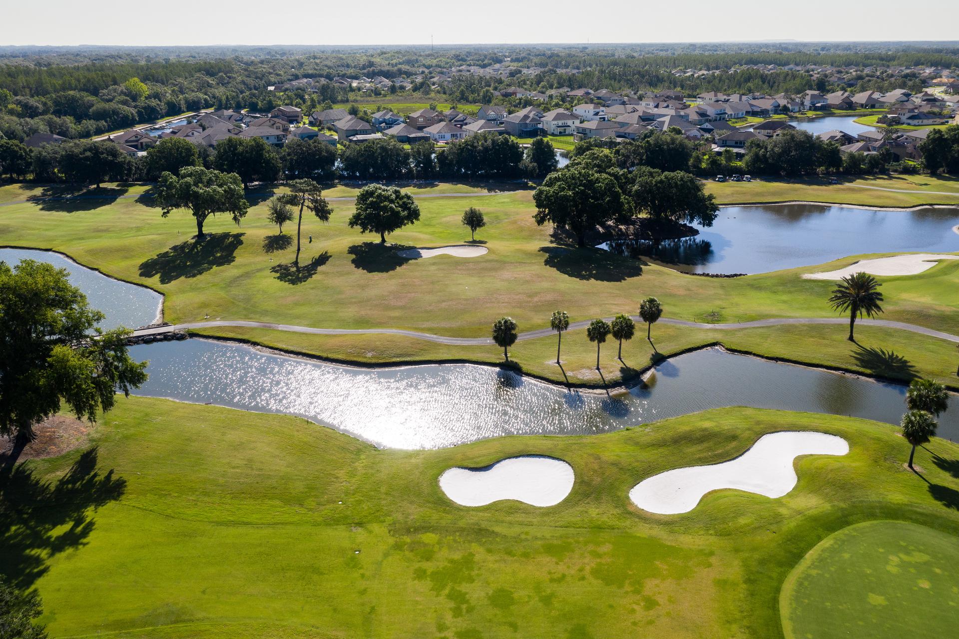 Overhead view of a fairway next to a water hazard nestled with sand bunkers