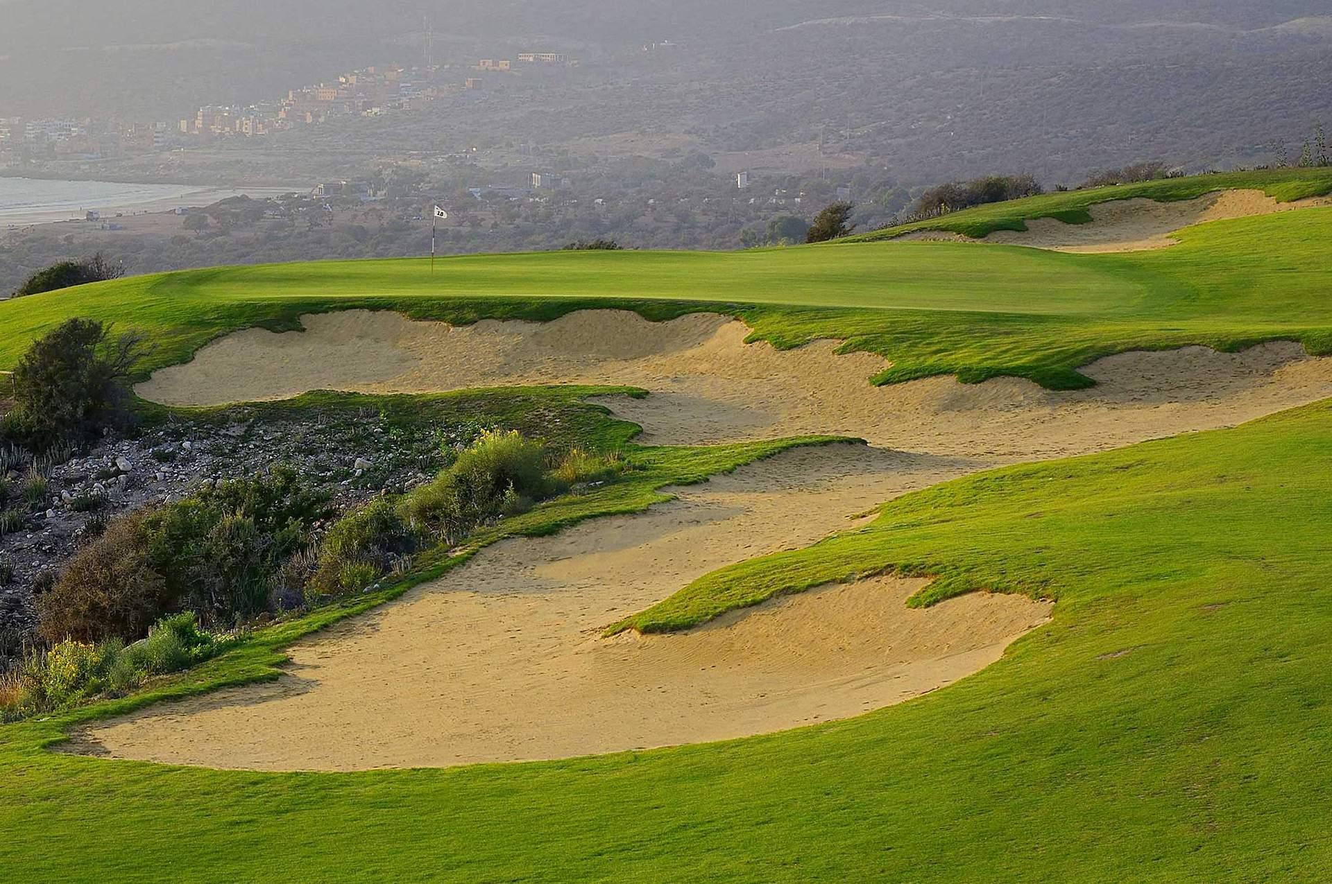 A fairway with a large sand bunker