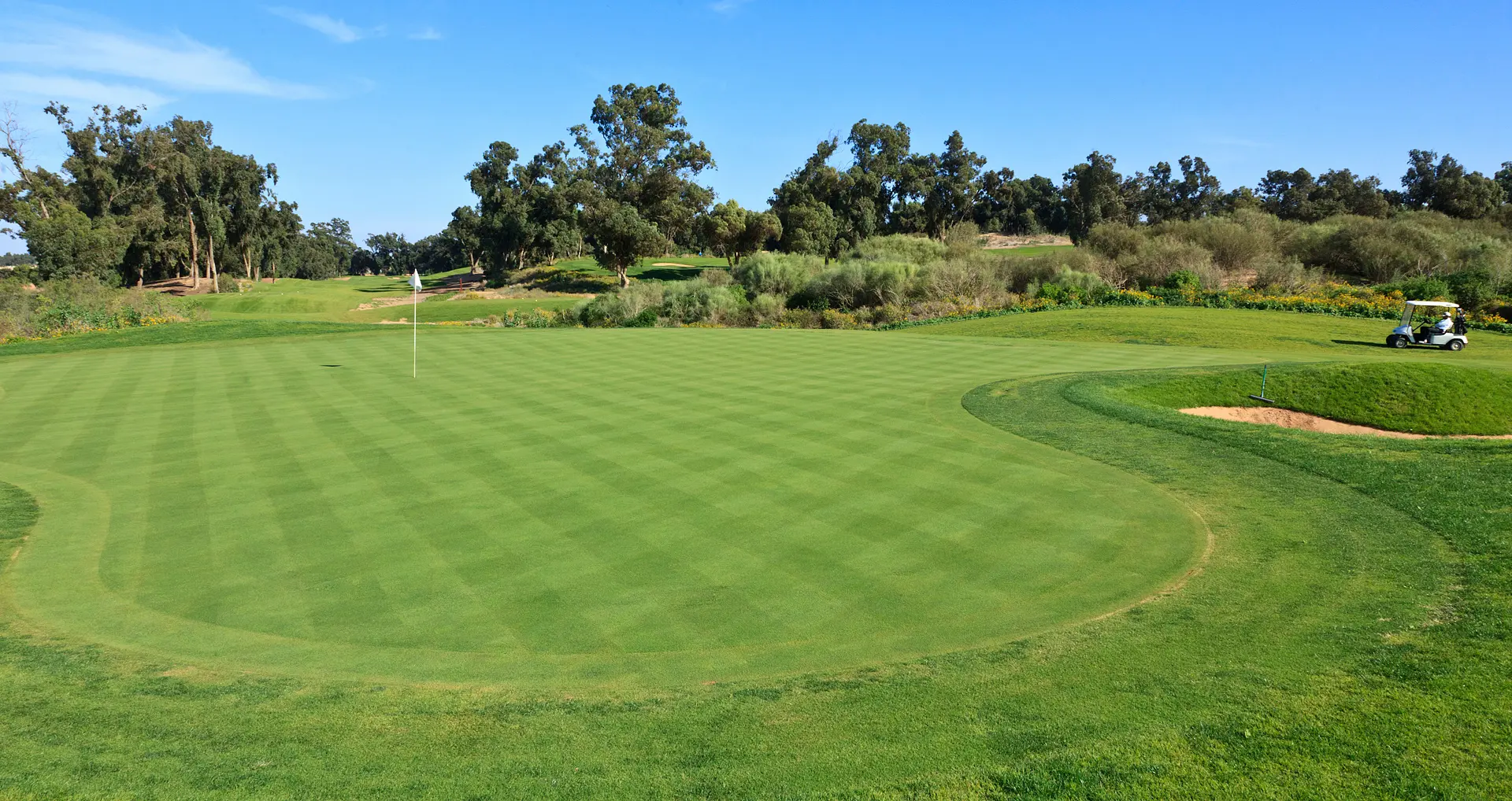 A well maintained water hazard nestled with a sand bunker