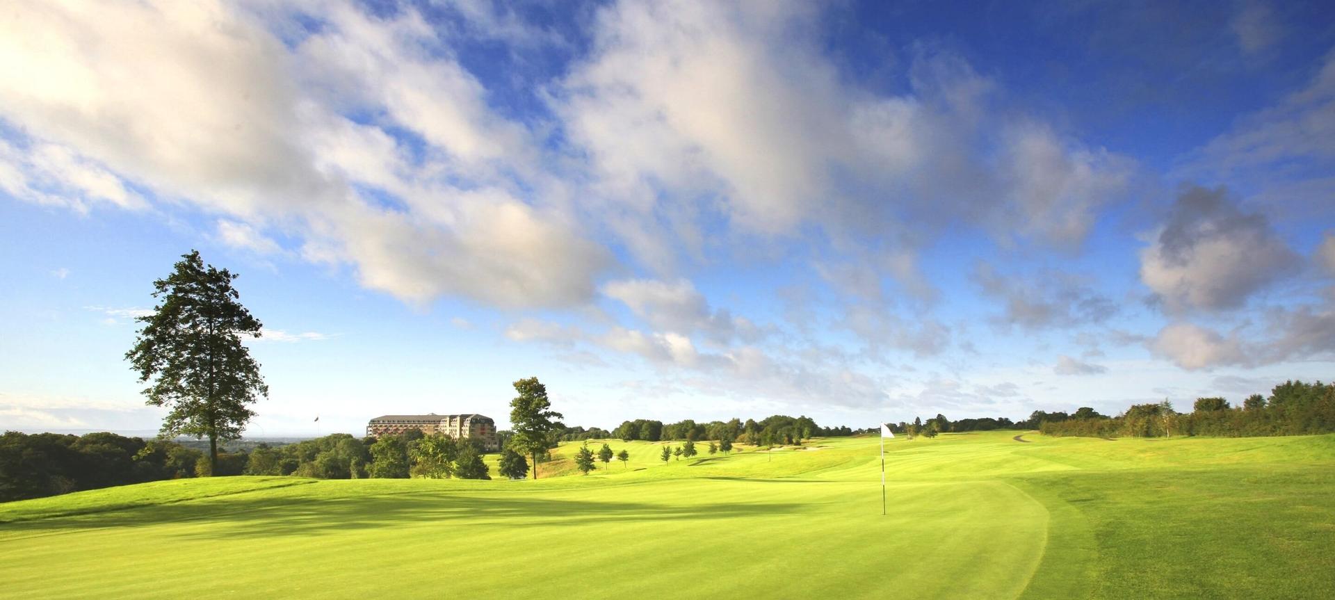A well maintained fairway under cloudy blue skies