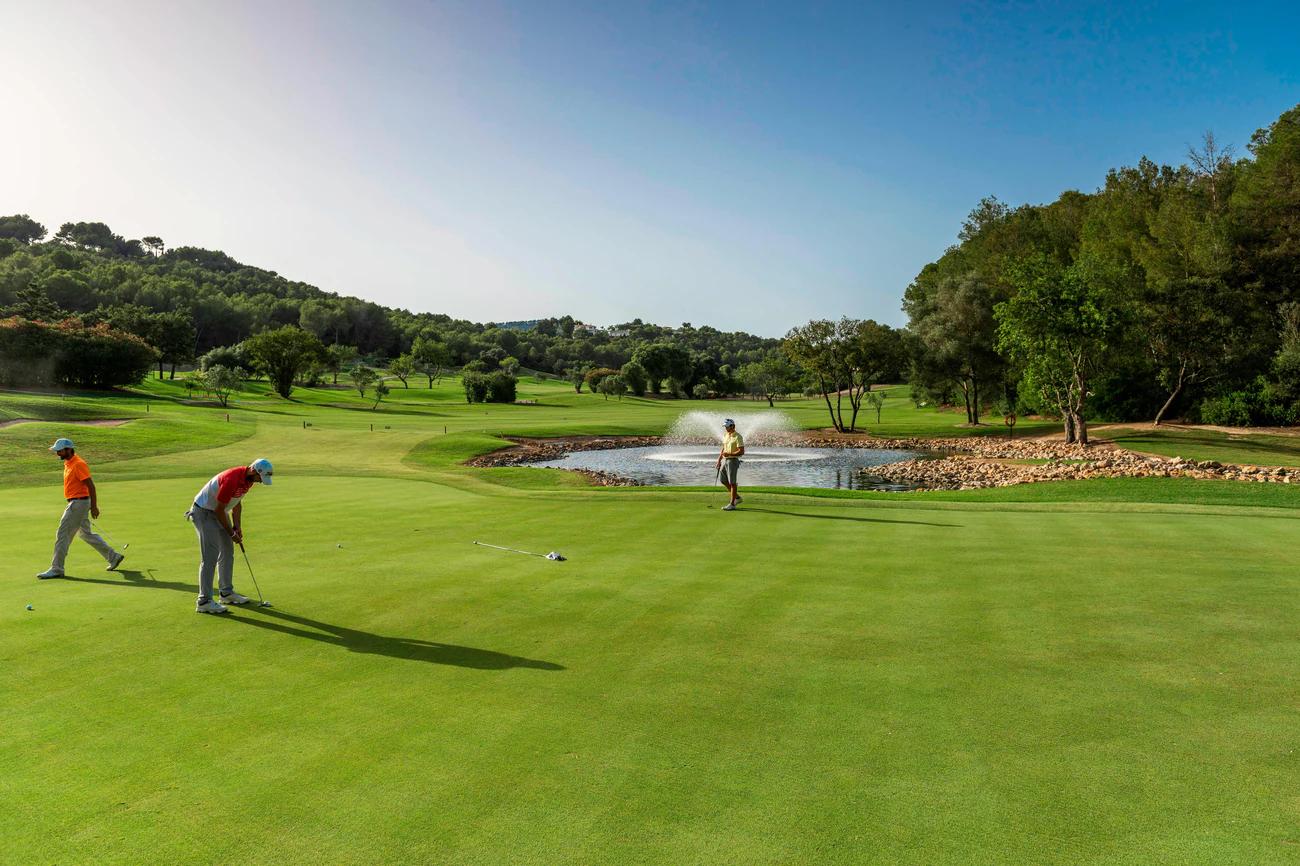 Golfers putting on a smooth green under clear skies