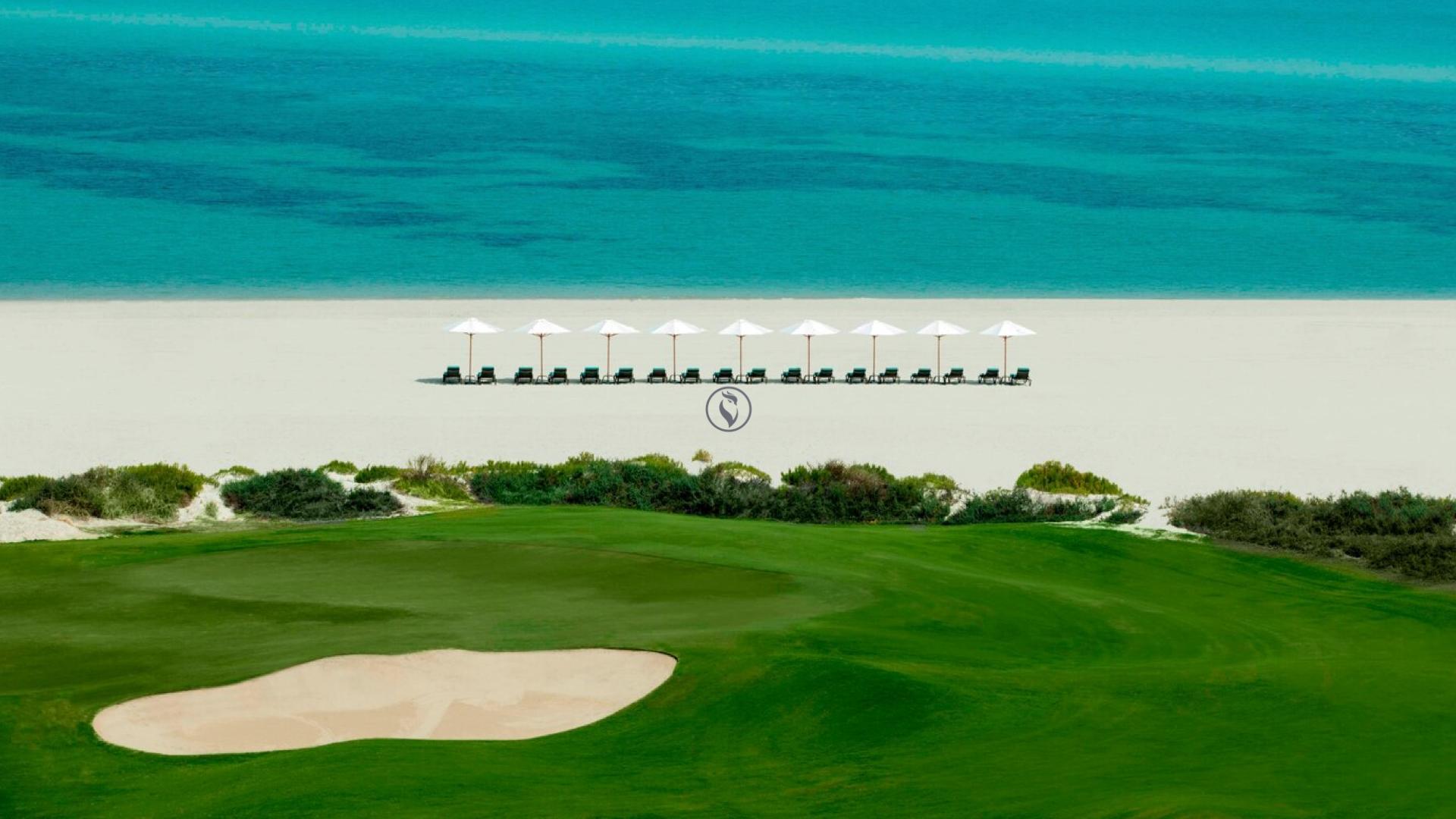 A smooth green next to a sand bunker with beach views