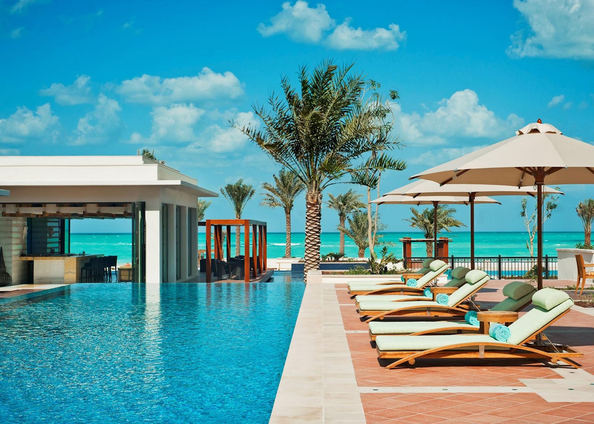 Outdoor swimming pool with sunbeds at The St Regis Saadiyat Island Resort