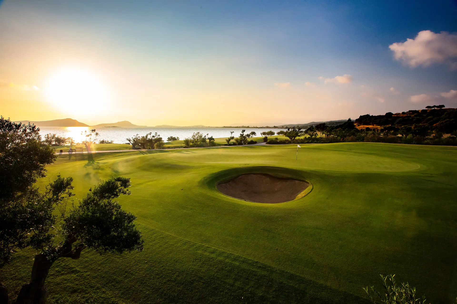 Sun shining over a well maintained fairway with a sand bunker
