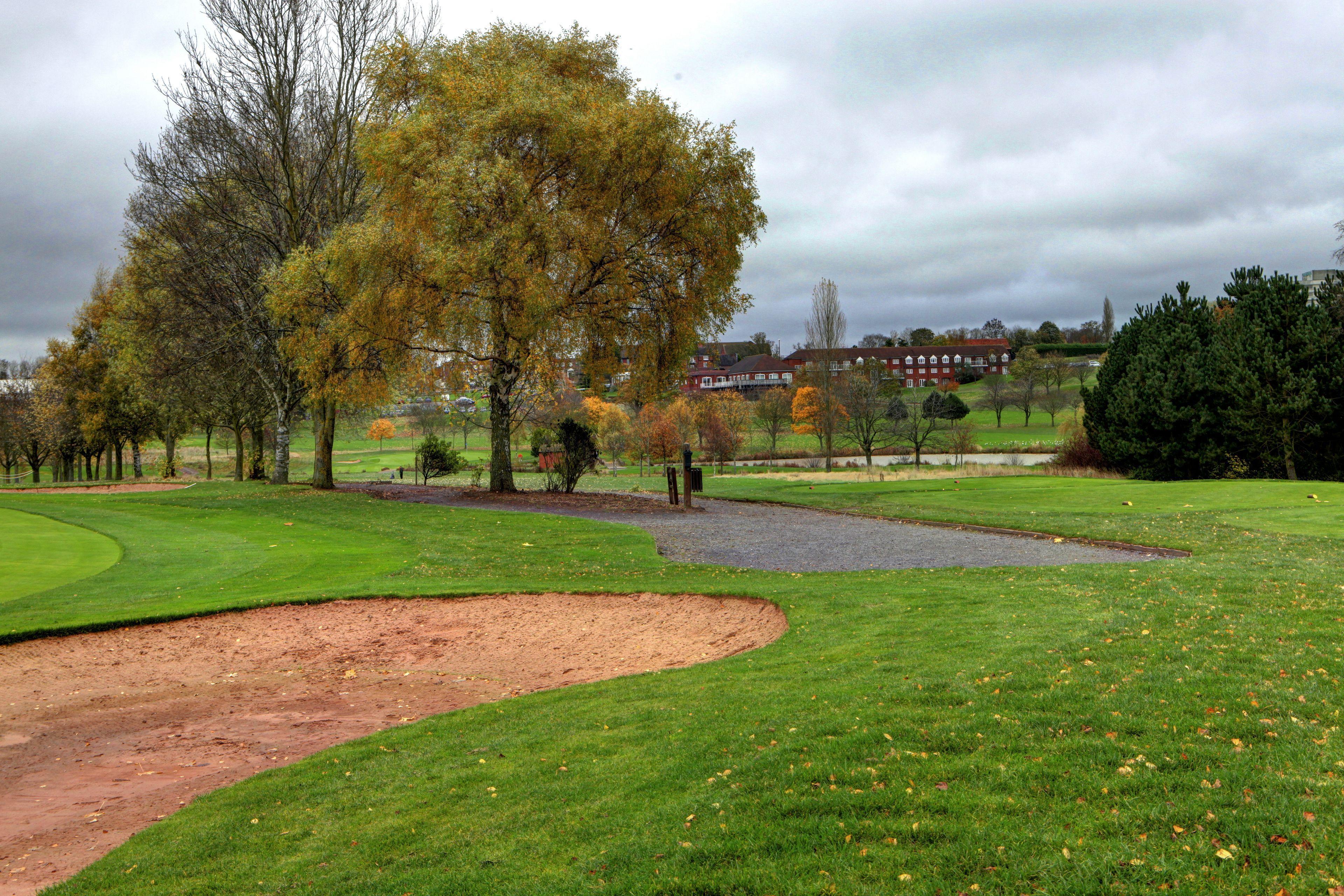 A sand bunker on the fairway with the Windmill Village Hotel, Golf Club & Spa building in the background