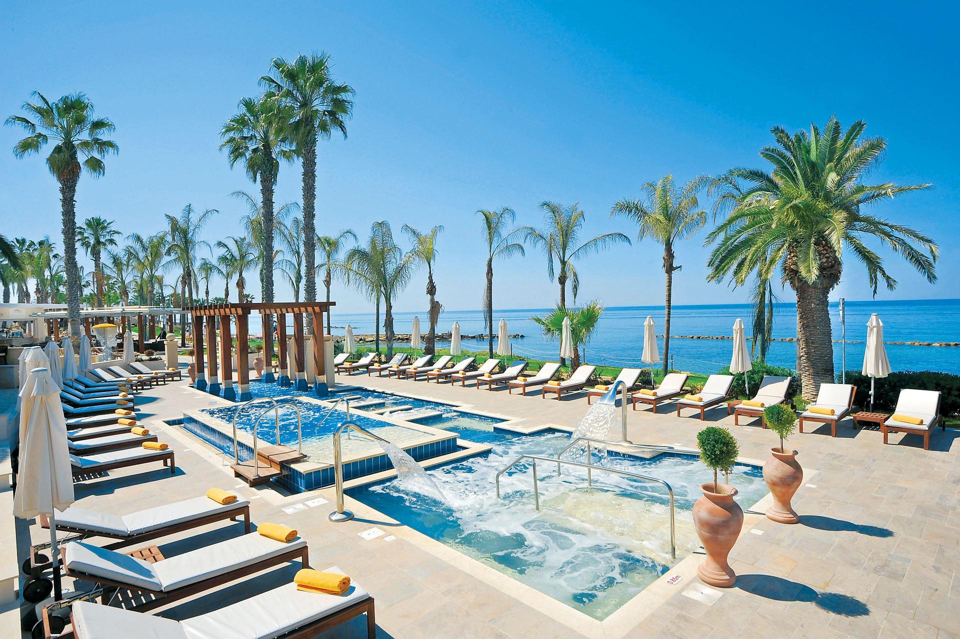 Outdoor swimming pool lined with sunbeds and palm trees