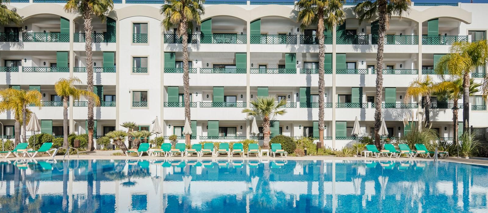 Outdoor swimming pool at Formosa Park Apartment Hotel lined with palm trees and sunbeds