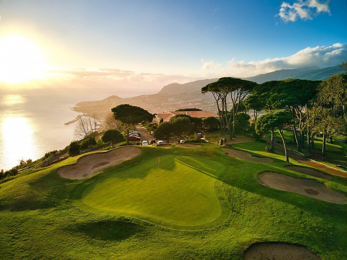 A smooth coastal green with the sun setting in the background