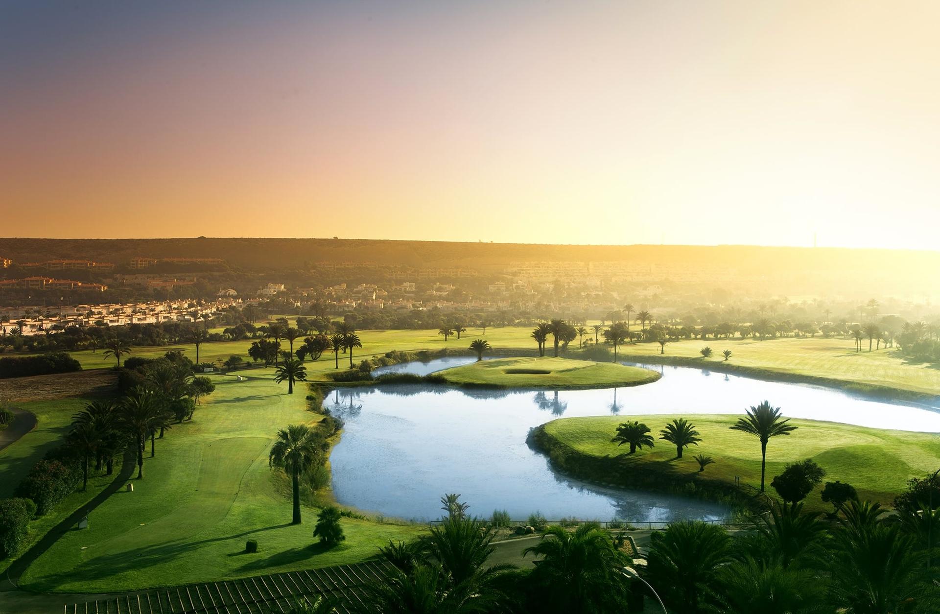 Sun shining over a well maintained fairway next to a water hazard