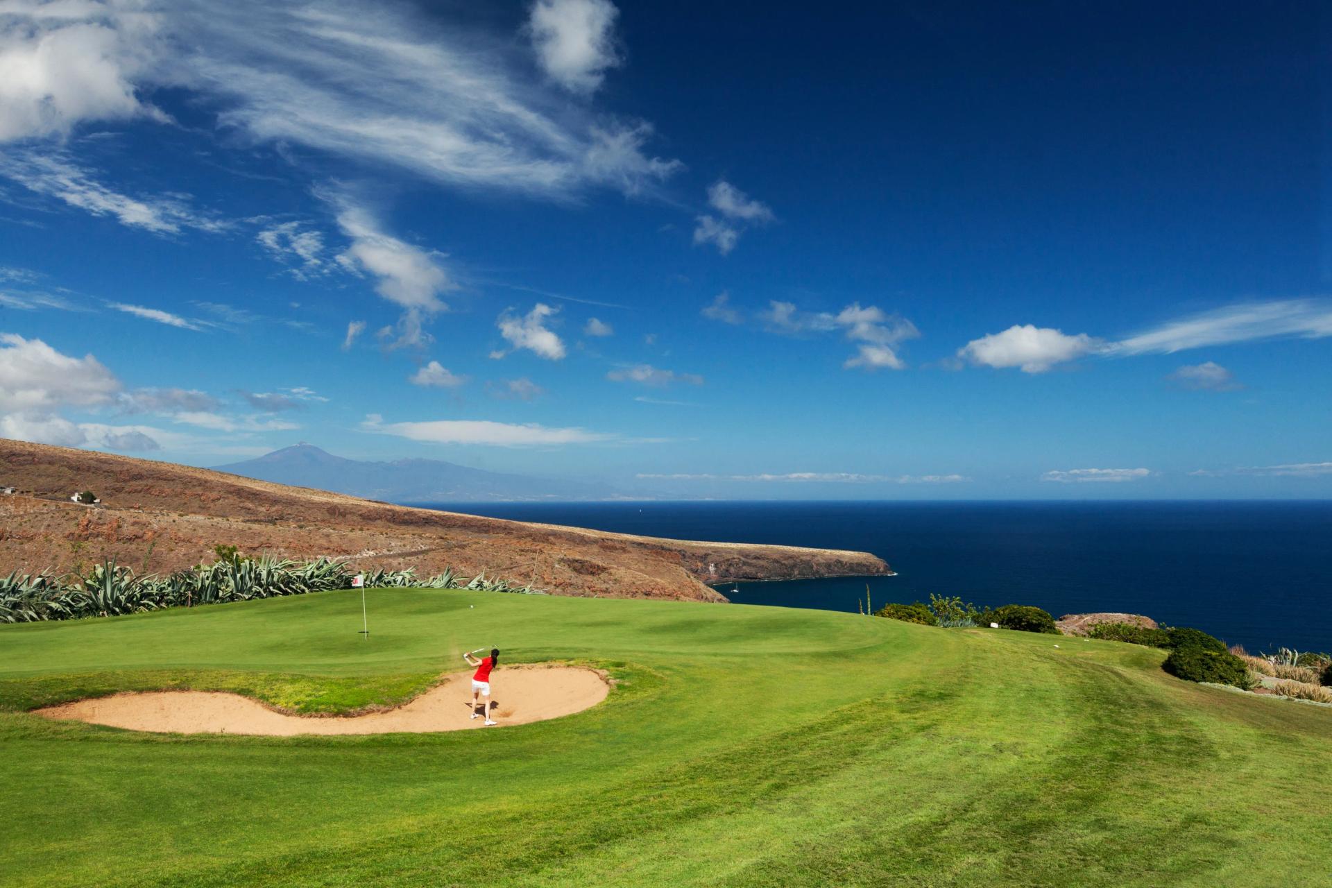 Golfer hitting out of a sand bunker onto a smooth green at Tecina Golf