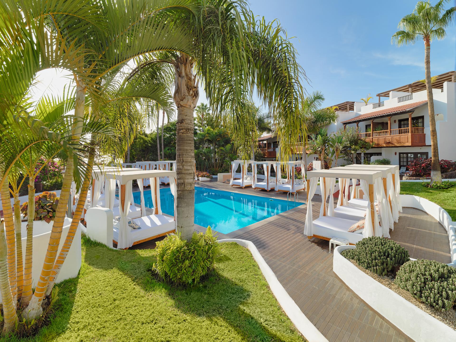 Panoramic view of an outdoor pool surrounded by cabanas