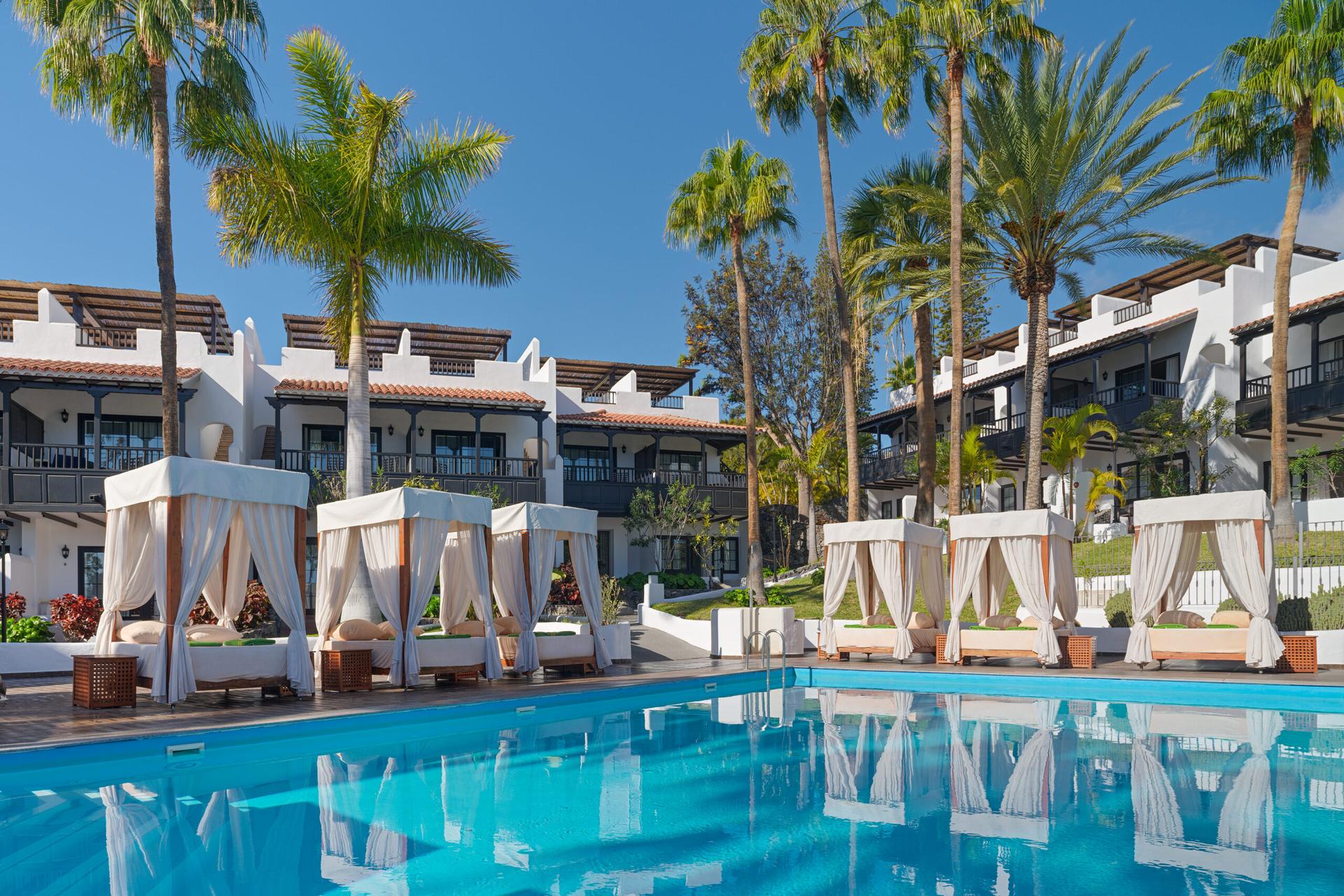 Outdoor pool at Hotel Jardin Tecina surrounded by cabanas