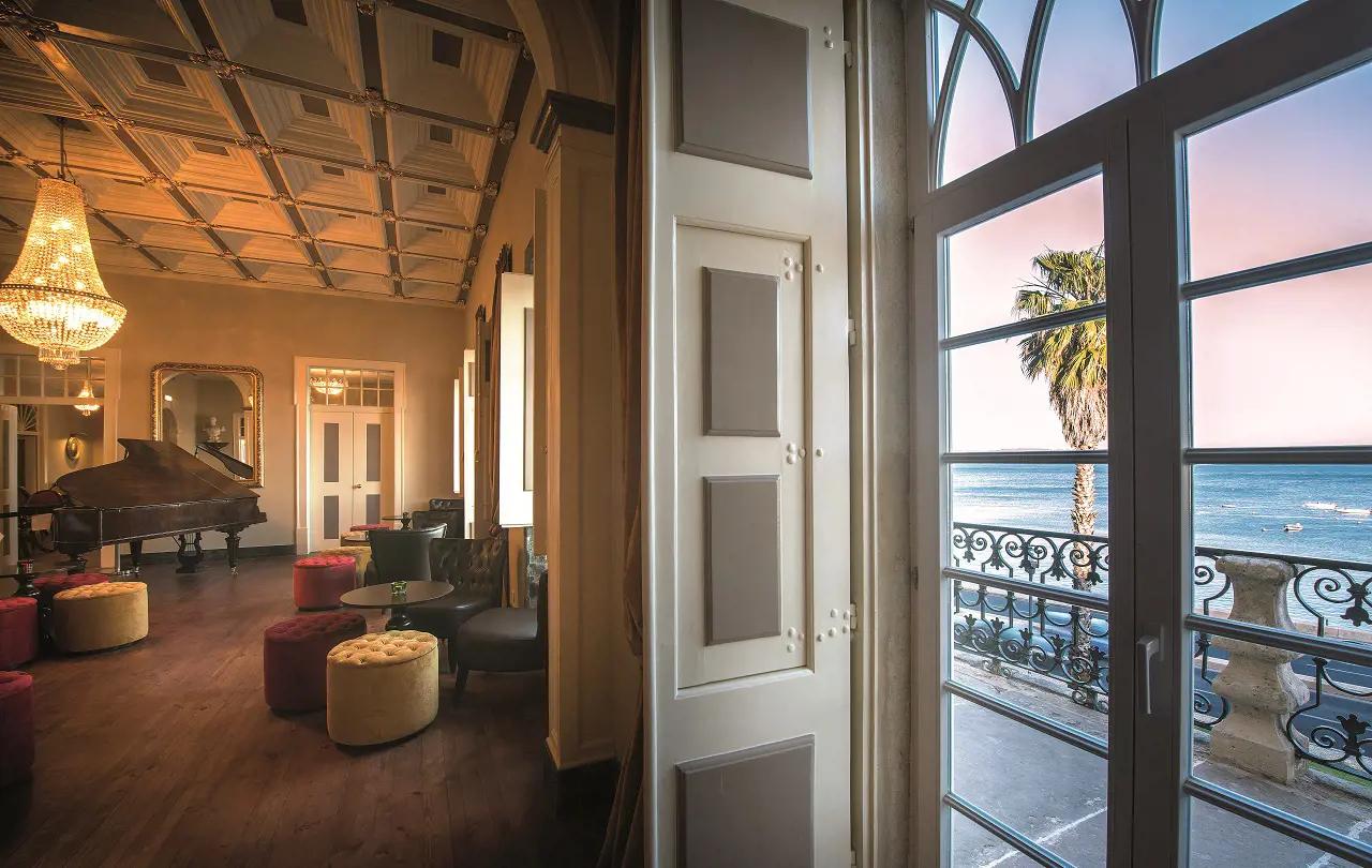 Indoor lounging area with a piano and balcony views of the outdoor pool
