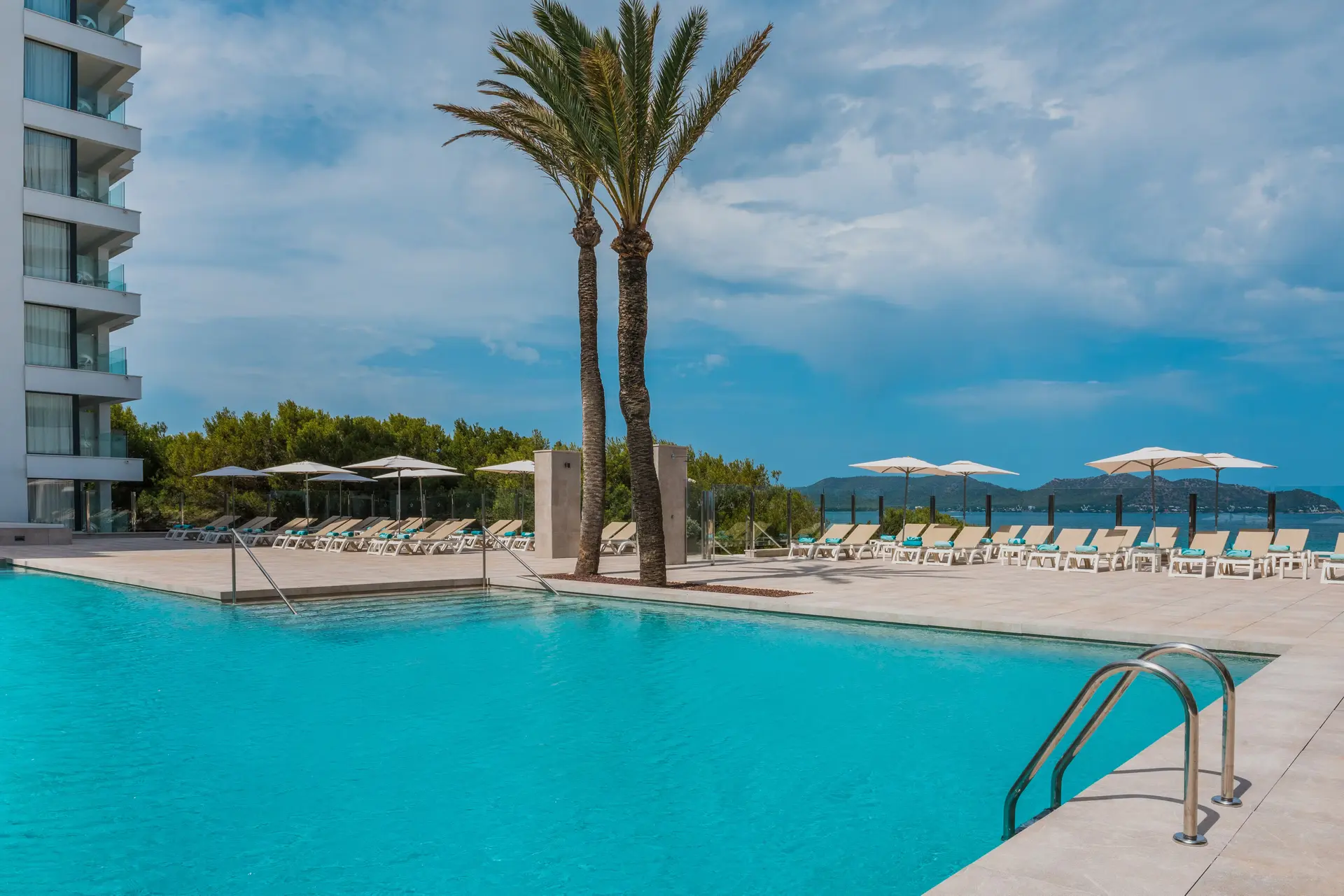 Outdoor swimming pool lined with sunbeds at Iberostar Waves Cala Millor