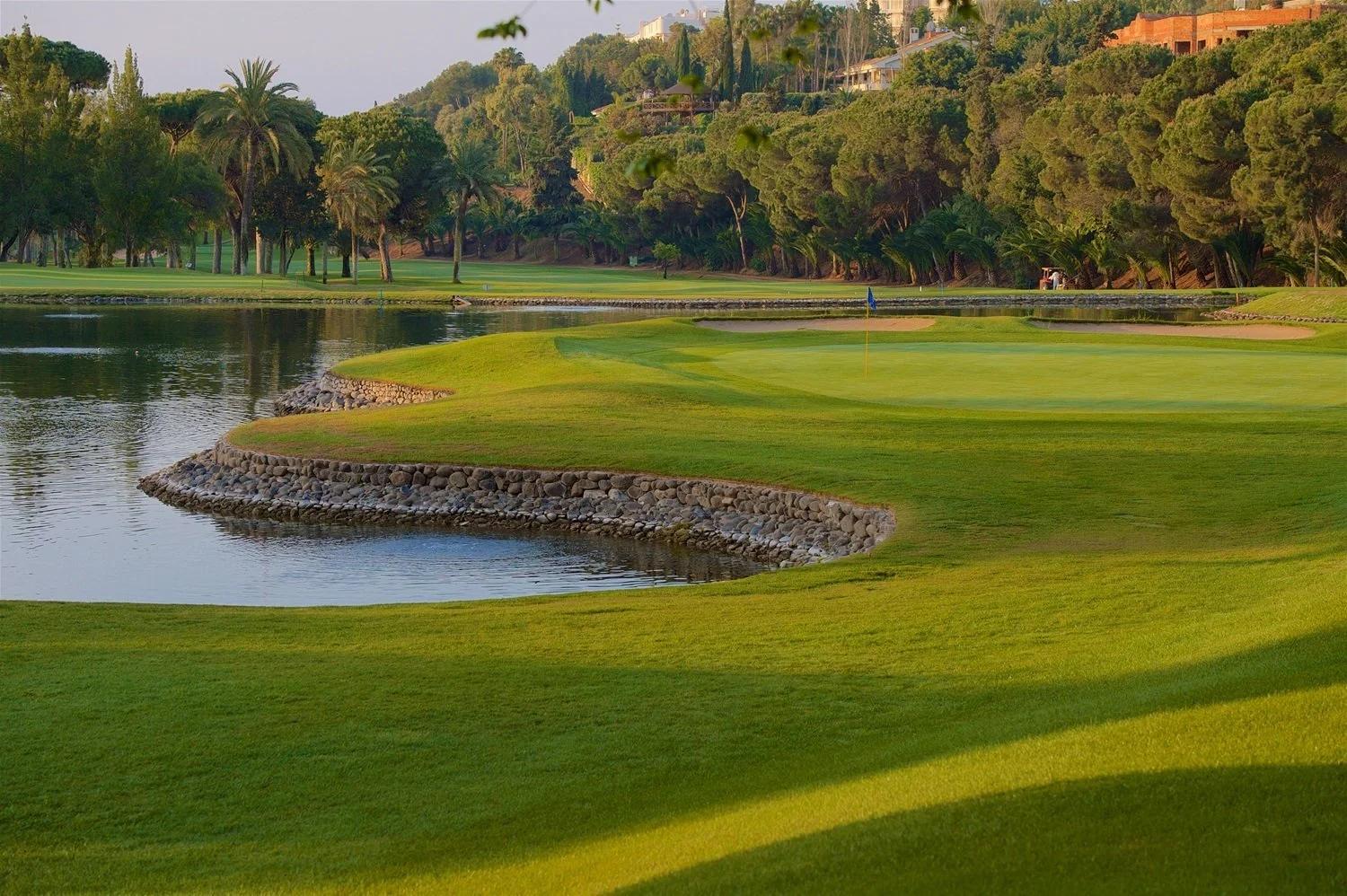 A well maintained fairway running besides a water hazard