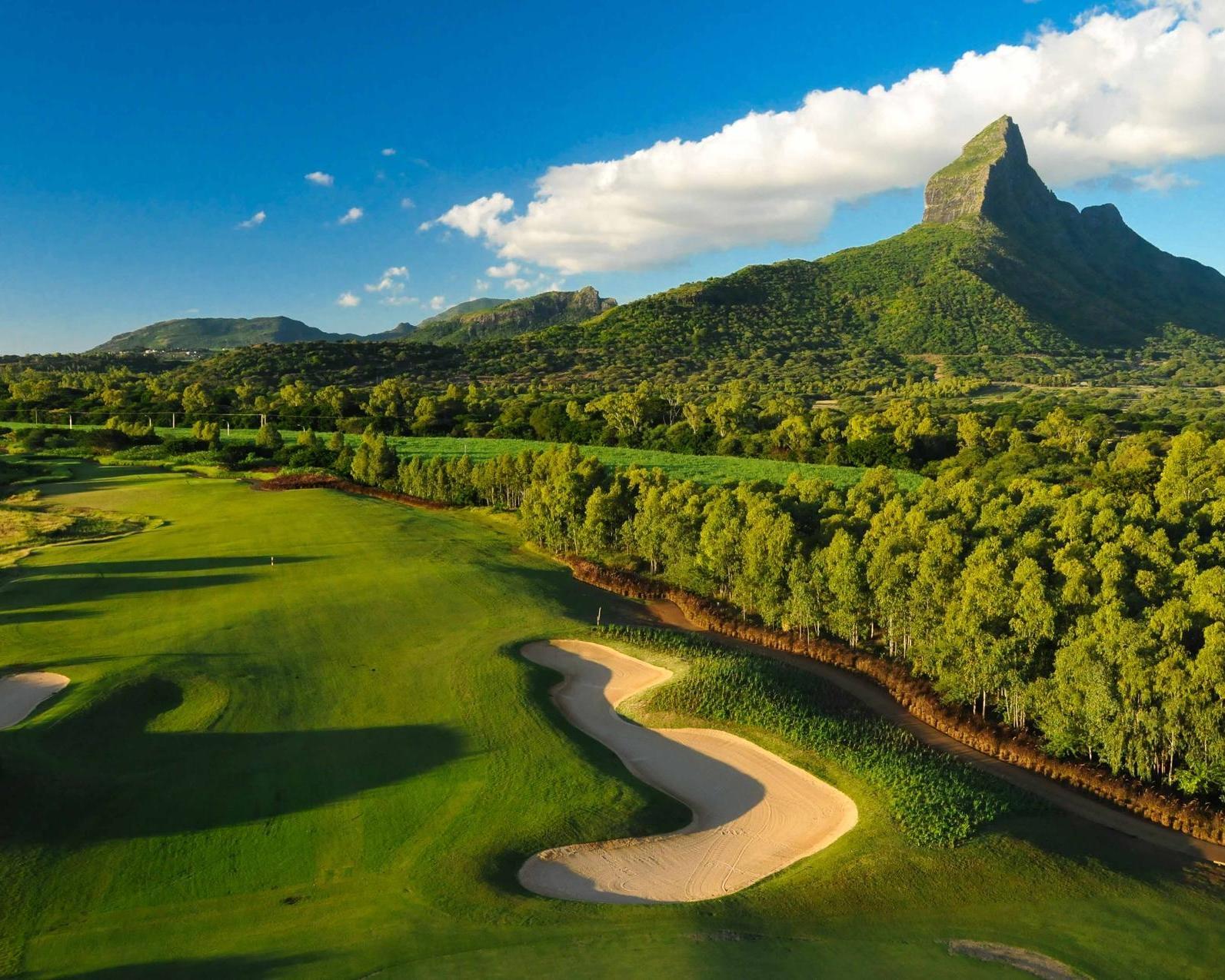 A well maintained fairway nestled with sand bunkers and distant mountain views