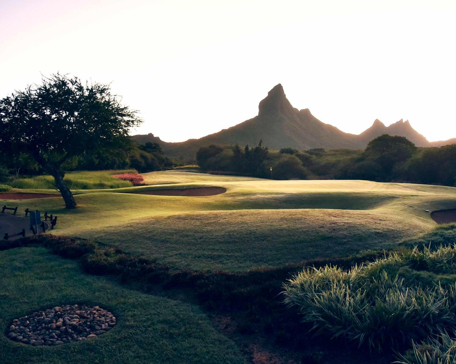 A well maintained fairway nestled with sand bunkers and mountain views in the distance